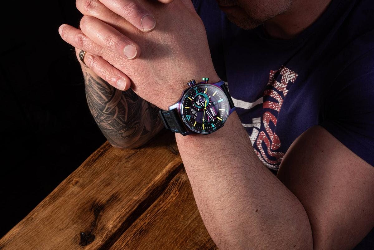 Man wearing a Vostok Europe watch with a rainbow PVD case and black strap
