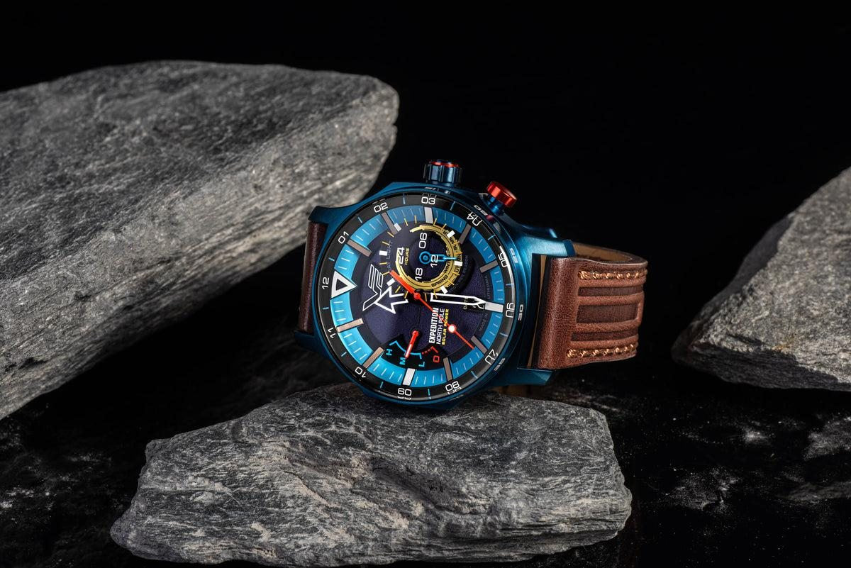 Vostok Europe Expedition North Pole Solar Power 24H watch with blue PVD case and brown leather strap resting on grey rocks