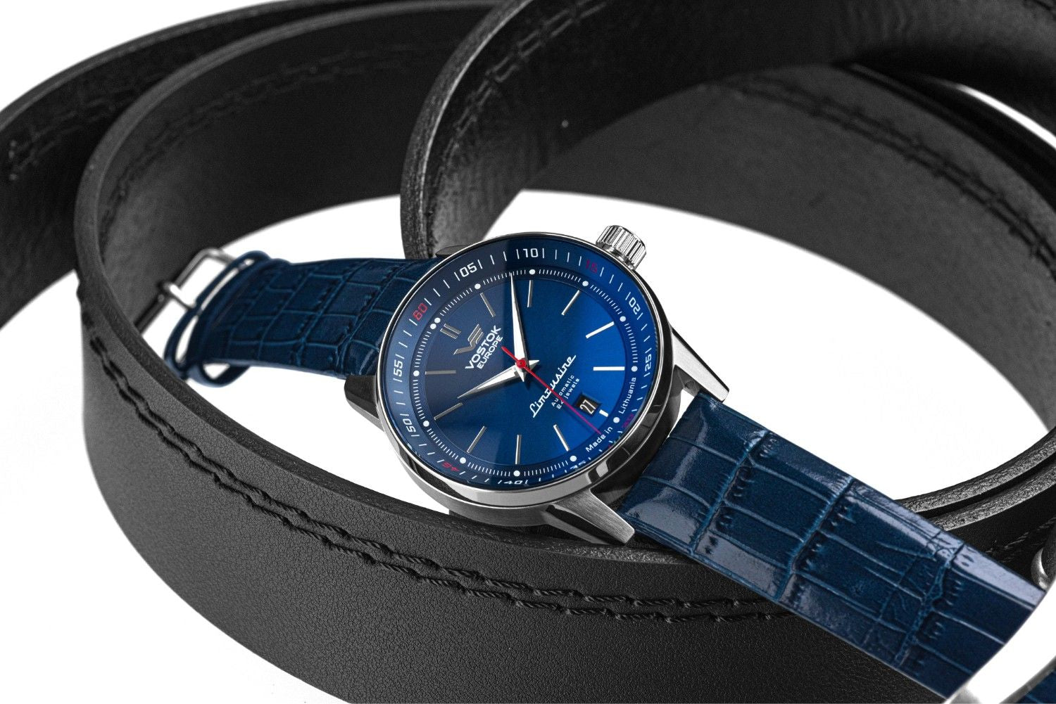 Vostok Europe Limousine blue dial dress watch with a polished stainless steel case, red seconds hand, date window and blue textured leather strap displayed with black leather belts